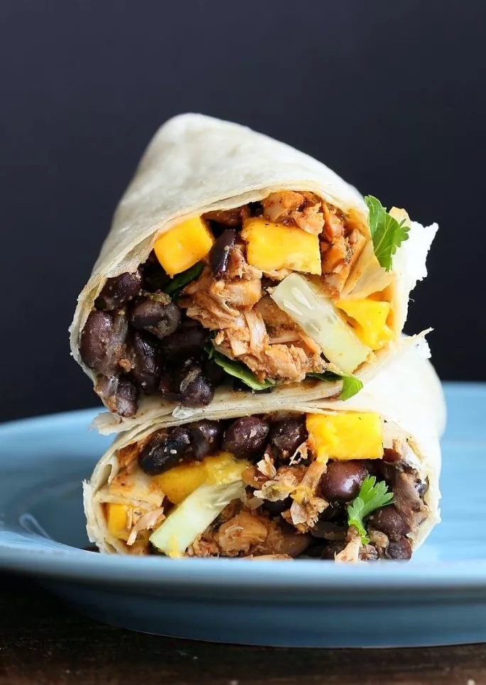 Image of two halves of a wrap filled with jackfruit, black beans, mango and cilantro.